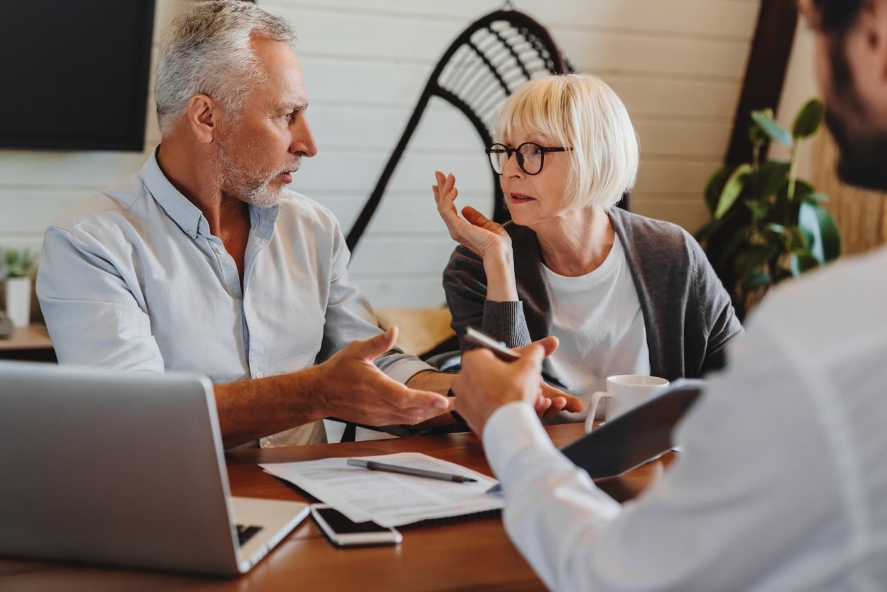 financial advisor giving retirement advice to old couple while they arguing at home interior